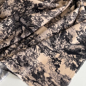 May include: Beige fabric with a black and white toile pattern of trees and branches. The fabric has a raw edge.