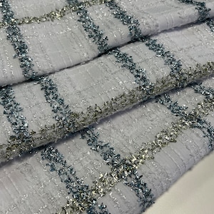 May include: White fabric with a checkered pattern. The fabric is decorated with silver and blue glitter thread.