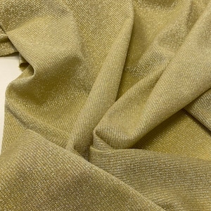 May include: A close-up of a gold fabric with a subtle shimmer. The fabric has a ribbed texture and is folded in a way that shows the texture and shimmer.
