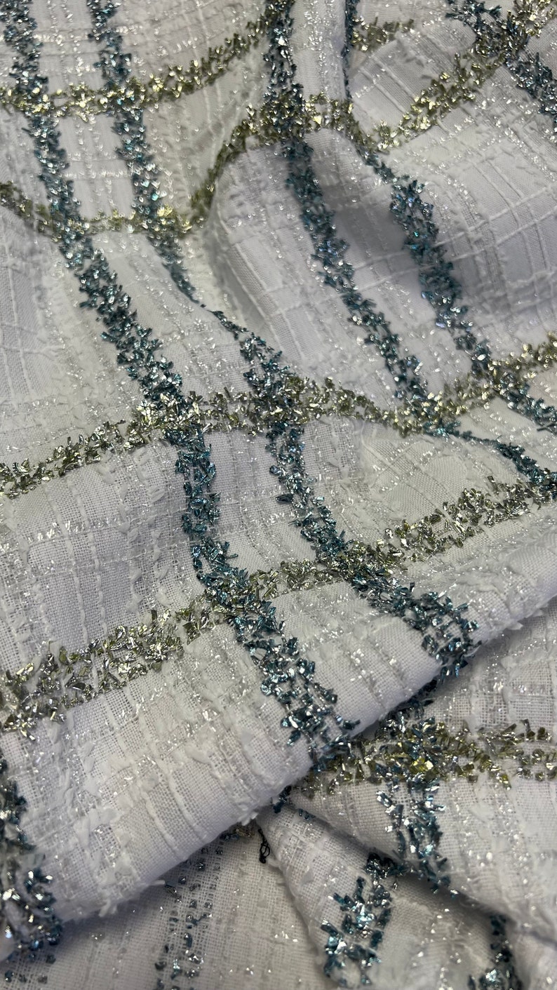May include: White fabric with a checkered pattern. The fabric is embellished with silver and blue glitter thread.
