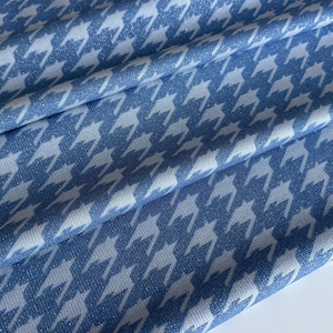 Pode incluir: Close-up de um tecido azul e branco com padrão pied-de-poule. O tecido está dobrado, mostrando a textura e o design do padrão. O padrão pied-de-poule é um design têxtil clássico.
