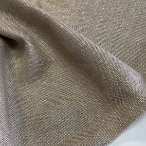 May include: A close-up of a beige fabric with a subtle shimmer. The fabric has a woven texture and a subtle sheen.