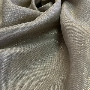 May include: Close-up of a silver fabric with a subtle shimmer. The fabric has a woven texture and a soft, drapey feel.
