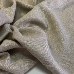May include: A close-up of a beige fabric with a subtle shimmer. The fabric has a woven texture and a slightly metallic sheen.
