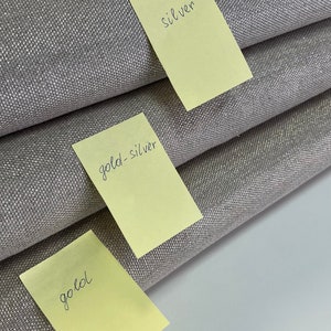 May include: Three fabric swatches labeled with sticky notes. The top swatch is labeled "silver", the middle swatch is labeled "gold-silver", and the bottom swatch is labeled "gold".