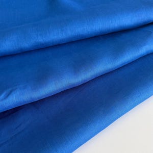 May include: A close-up of a folded piece of bright blue fabric. The fabric has a smooth, slightly textured surface.