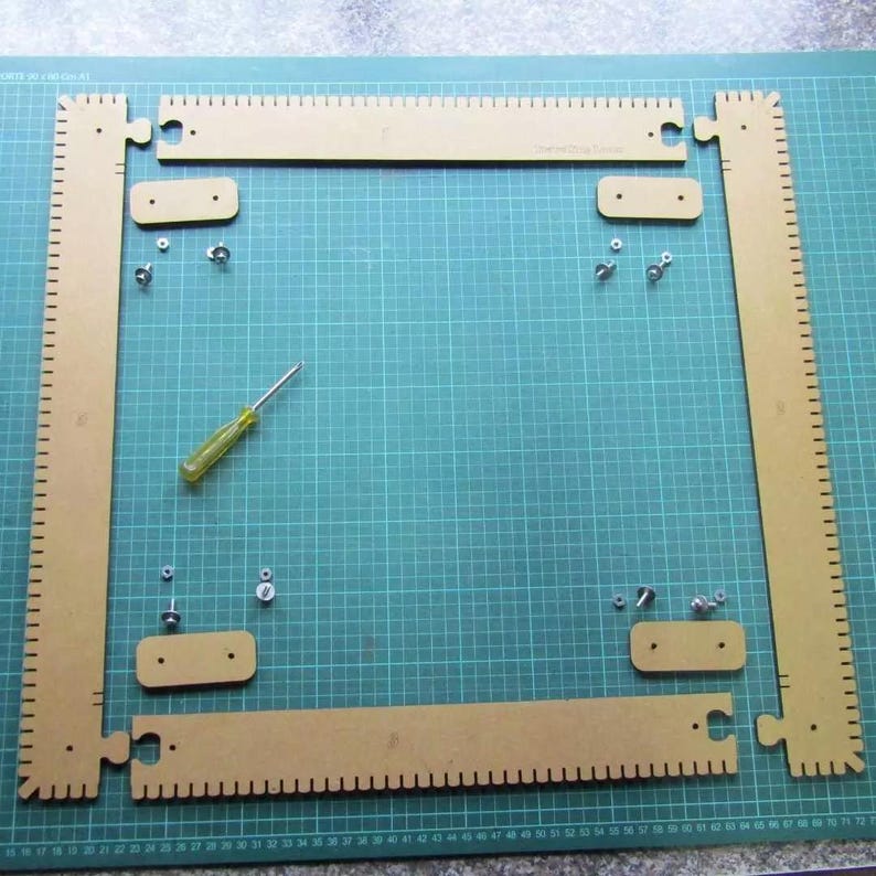 May include: A set of four tan, notched rectangular frame pieces with puzzle-style connectors, four small rectangular joining plates, eight metal screws, eight metal nuts, and a small screwdriver with a yellow handle for assembly.
