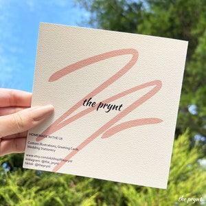 Puede incluir: Tarjeta cuadrada de color crema con un dise&ntilde;o rosa abstracto grande y el texto "the prynt" en negro. El texto adicional incluye "HOMEMADE IN THE UK" y detalles para ilustraciones personalizadas, tarjetas de felicitaci&oacute;n y papeler&iacute;a de boda.
