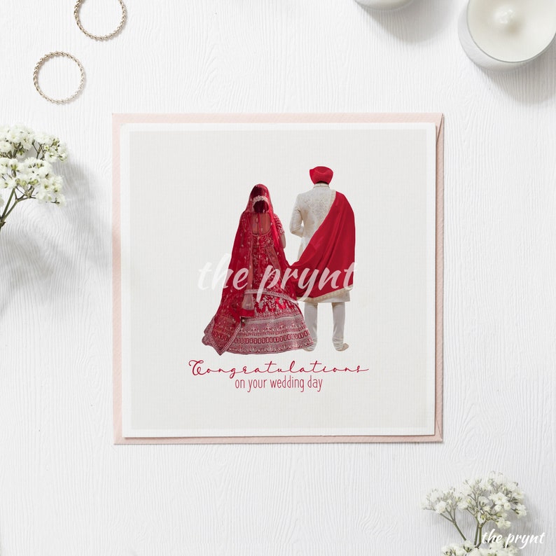 Puede incluir: Tarjeta de boda cuadrada con una ilustraci&oacute;n de una pareja con vestimenta tradicional. La novia lleva un vestido rojo, y el novio un atuendo color crema con un chal rojo. Incluye el texto "Felicidades en el d&iacute;a de tu boda."