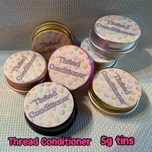 May include: A collection of small, round tins of thread conditioner. Each tin features a lid printed with "Thread Conditioner" and a pattern of colourful hearts. The tins are in various colours, and are approximately 5g each.