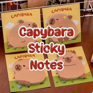 May include: Four square sticky notes with capybara designs. Each note has a light brown capybara illustration on a yellow background with the word "Capybara" at the top. The words "Capybara Sticky Notes" are in large red letters.