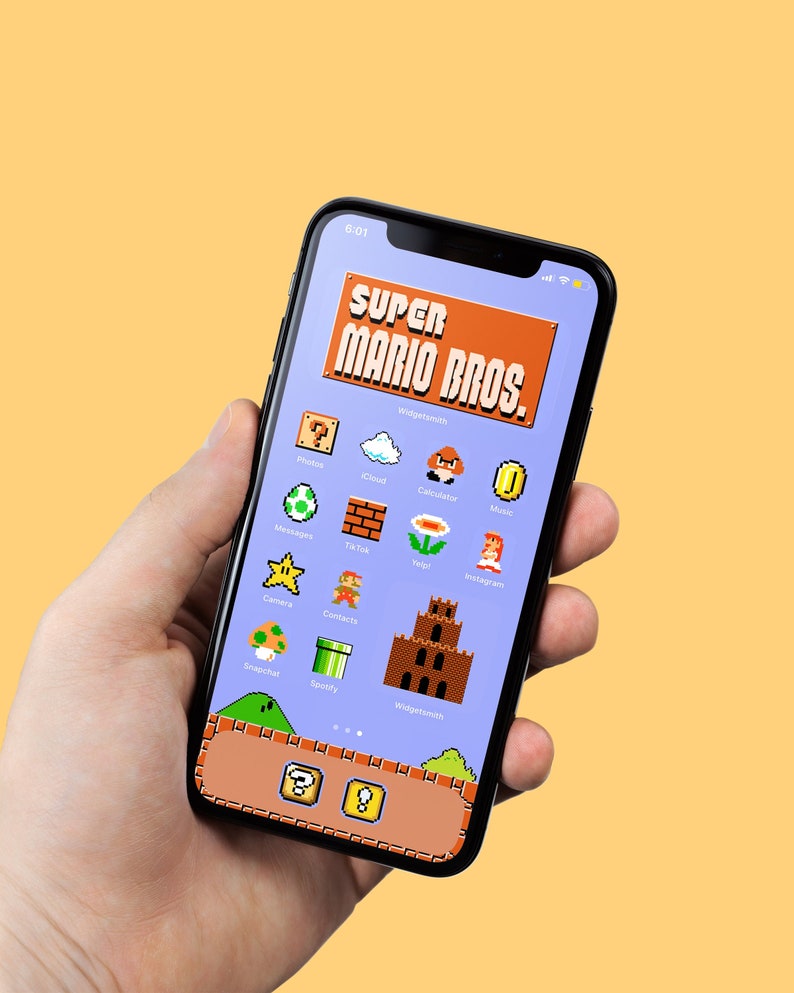 May include: A smartphone with a blue background and a Super Mario Bros. themed home screen. The icons are pixelated and resemble the classic video game. The phone is being held in a hand.