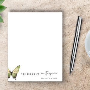 May include: A white notepad with a green butterfly illustration and the text "You are God's masterpiece Ephesians 2:10 (NIV)".