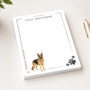 May include: A white rectangular notepad featuring the text A NOTE FROM VICKY WHITTEMORE at the top, the words GERMAN SHEPHERD vertically along the left border, a full-color illustration of a German Shepherd dog, and three black paw prints.