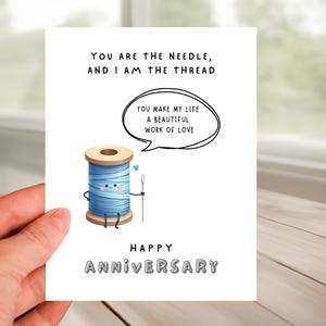 May include: A white card with a cartoon illustration of a spool of thread and a needle. The card reads "You are the needle, and I am the thread. You make my life a beautiful work of love. Happy Anniversary."