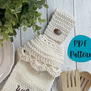 May include: A white crocheted dish towel holder with a scalloped edge and a button. The holder is attached to a white kitchen towel with the word "Welcome" embroidered on it. The image also includes a wooden spoon and a blue circle with the text "PDF Pattern".