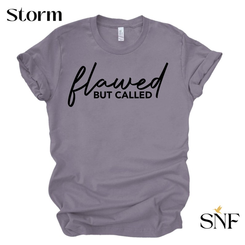 May include: A purple t-shirt with the text "flawed but called" in black script.