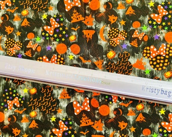 May include: Black and orange fabric with a Halloween-themed print featuring Mickey Mouse ears, bats, stars, pumpkins, and haunted houses. The fabric has a distressed, vintage look.