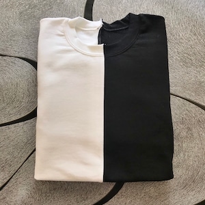 May include: A folded white and black t-shirt with a vertical seam down the center.