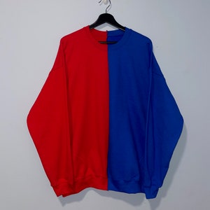 May include: A red and blue sweatshirt with a vertical split down the middle. The left side is red and the right side is blue.