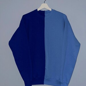 May include: A blue and light blue sweatshirt with a vertical seam down the center.
