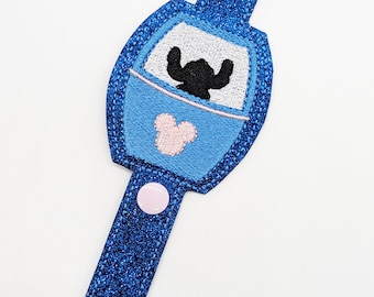 May include: Blue and white glitter wristlet keychain with a blue and white Stitch character in a blue and pink spaceship with a pink Mickey Mouse head on the front.