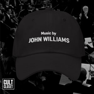 Może przedstawiać: Czarna czapka bejsbolówka z białym haftem z napisem "Music by JOHN WILLIAMS".