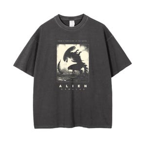 May include: A black t-shirt with a vintage-style graphic of the Alien creature from the movie "Alien." The graphic is in white and features the text "There's something in the water" and "Alien Romulus."