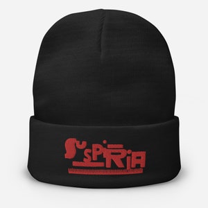 May include: Black beanie with a red embroidered logo that says "Suspiria" with a line underneath.