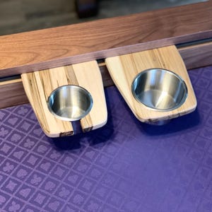 May include: Two wooden cup holders with stainless steel cups attached to a wooden surface. The surface is purple with a repeating pattern.