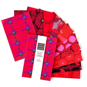 Puede incluir: Un conjunto de diez postales con diversos diseños rojos y rosas, presentadas en abanico. Las postales son en blanco en la parte posterior y llevan el texto "LEILA SIMON HAYES PACK OF 10 POST CARDS BLANK ON BACK".
