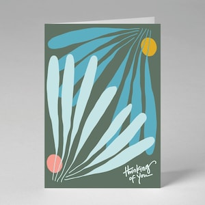 Puede incluir: Una tarjeta de felicitación rectangular con fondo verde oliva oscuro que presenta formas abstractas de hojas en azul claro y azul verdoso, un pequeño círculo amarillo y un círculo rosa. El texto "Thinking of you" aparece en blanco en la esquina.