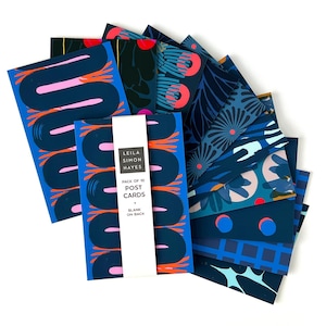 May include: A collection of postcards with various abstract designs in shades of blue, pink, and orange. The postcards are fanned out, with a package of 10 cards visible, featuring the text "LEILA SIMON HAYES PACK OF 10 POST CARDS * BLANK ON BACK."