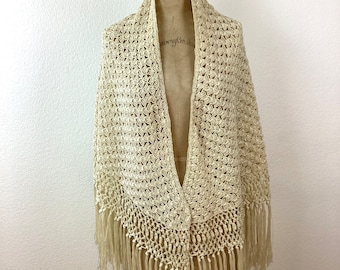 May include: A cream-colored crocheted shawl with fringe. The shawl is draped over a dress form.