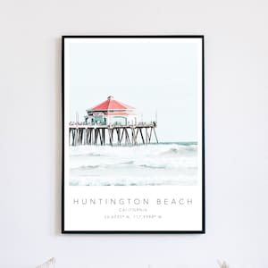 Könnte beinhalten: Eine Aquarellillustration des Huntington Beach Piers in Kalifornien. Der Pier ist eine Holzkonstruktion mit einem Gebäude mit rotem Dach am Ende. Der Pier ragt ins Meer hinaus, wo Wellen gegen ihn schlagen. Der Text "HUNTINGTON BEACH, CALIFORNIA, 33.6595° N, 117.9988° W" ist unter dem Bild gedruckt.