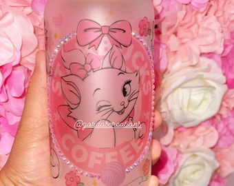 May include: A frosted glass jar with a bamboo lid featuring a pink cartoon cat with a pink bow and the text "Coffee" in a circle with rhinestones around it. The text "@gordascreations" is also included on the jar.