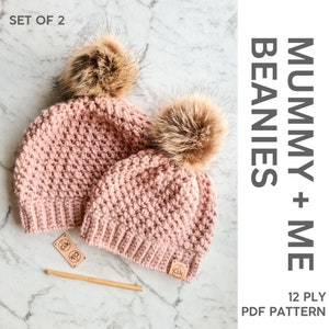Pode incluir: Conjunto de dois chapéus de crochê cor-de-rosa com pompons de pele sintética castanho. Os chapéus são etiquetados como "Mummy + Me Beanies" e "12 Ply PDF Pattern".