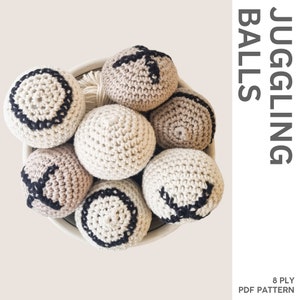 Puede incluir: Ocho pelotas de malabares de crochet en un tazón blanco. Las pelotas son beige con diseños geométricos negros. Las pelotas son de 8 cabos y el patrón está disponible para descargar en PDF.