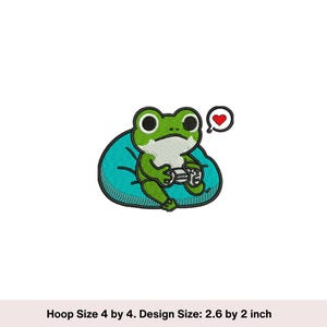 May include: Green frog with big eyes sitting in a blue beanbag chair, holding a video game controller. The frog is looking to the right and has a red heart in a speech bubble above its head.  Hoop Size 4 by 4. Design Size: 2.6 by 2 inch.