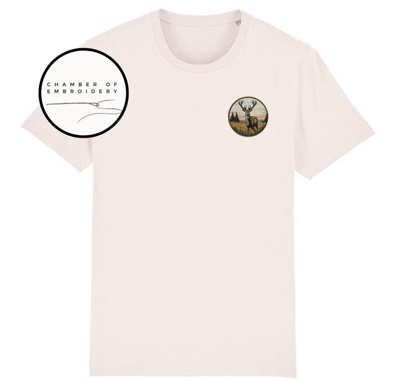 May include: A light pink short-sleeve t-shirt featuring a circular embroidered patch on the left chest depicting a stag in a field. A circular logo in the upper left corner contains the text CHAMBER OF EMBROIDERY with a needle and thread graphic.