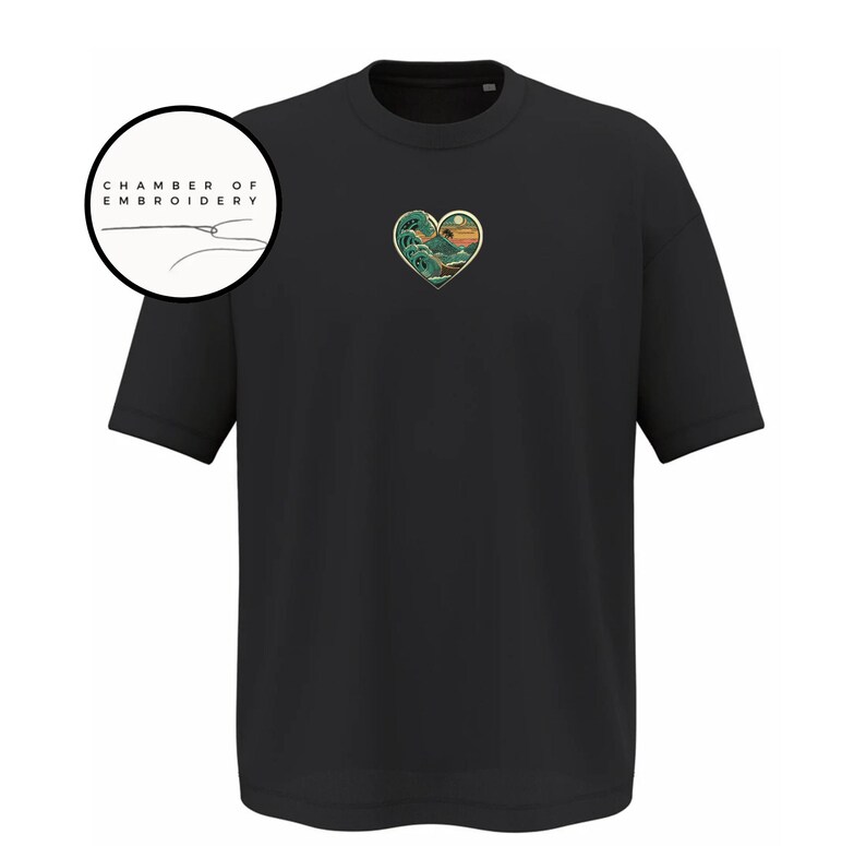 Może przedstawiać: Czarny t-shirt z kr&oacute;tkim rękawem z małym haftem w kształcie serca na piersi, przedstawiającym stylizowaną falę oceaniczną i zach&oacute;d słońca. Okrągłe logo w lewym g&oacute;rnym rogu zawiera napis CHAMBER OF EMBROIDERY oraz ikonę igły z nitką.