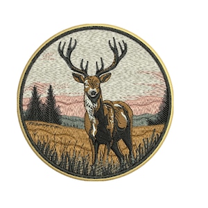 May include: A circular embroidered patch featuring a brown deer with large antlers standing in a field of tall grass. The background depicts a landscape with dark green pine trees and a pale pink sky, all enclosed by a thick black and gold border.