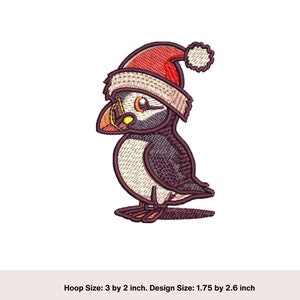 May include: Embroidered design of a cartoon puffin wearing a red Santa hat with white trim. The puffin is facing left and has a yellow beak and black eyes. The design is 1.75 inches by 2.6 inches.
