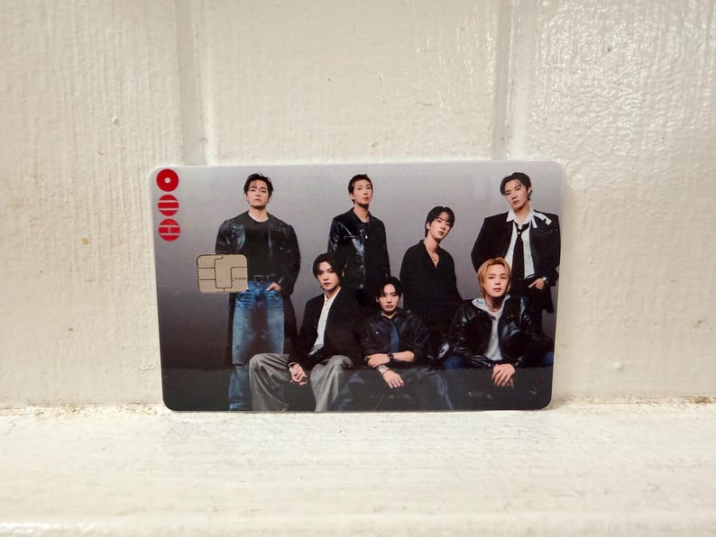 Puede incluir: Una tarjeta rectangular con un grupo de siete personas. La tarjeta tiene un fondo degradado plateado y gris. La esquina superior izquierda tiene tres c&iacute;rculos rojos y un chip. Las personas visten chaquetas, camisas y vaqueros negros.