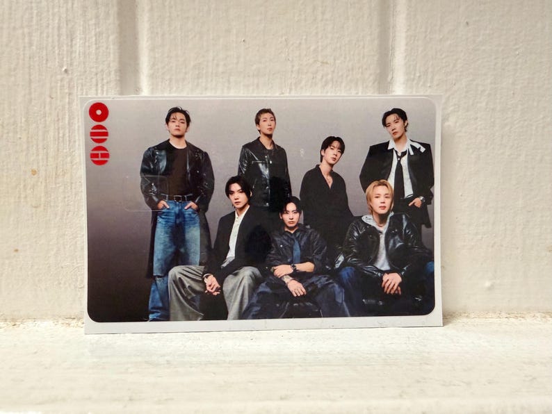 Puede incluir: Tarjeta rectangular con un grupo de siete personas. Todos visten diferentes atuendos, incluyendo chaquetas de cuero negras, blazers y vaqueros. La tarjeta tiene un borde blanco y un dise&ntilde;o rojo en la esquina superior izquierda. El fondo es un degradado de gris.