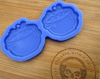 Könnte beinhalten: Eine blaue Silikonform mit zwei Kesselformen. Jeder Kessel hat einen Griff und Blasen im Inneren. Die Form ist mit einem Twist entworfen.