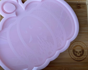 May include: A pink silicone mold shaped like a pumpkin with a spiderweb design and a small circle at the top for hanging. The mold is designed for making resin crafts.