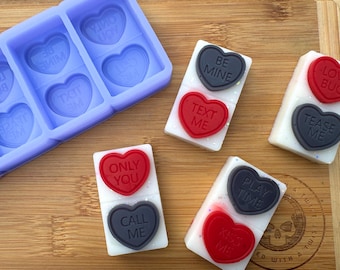 Op de afbeelding: Twee rijen hartvormige wax melts met verschillende Valentijnsdag-berichten. De bovenste rij heeft "Be Mine", "Text Me", "Only You" en "Call Me". De onderste rij heeft "Play Time", "Kiss Me", "Love Bug" en "Tease Me".