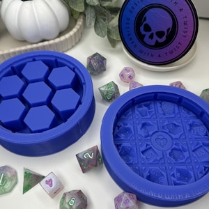 Può includere: Due stampi in silicone blu per realizzare dadi in resina. Uno stampo ha un design esagonale con sei cavità individuali. L'altro stampo ha un design circolare con un motivo dettagliato di facce dei dadi. Gli stampi sono progettati con un tocco di originalità.