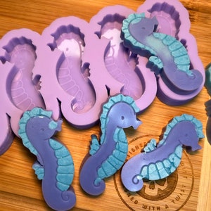 May include: Purple and blue silicone mold with multiple seahorse shapes.  The mold is filled with purple and blue seahorse-shaped soaps.